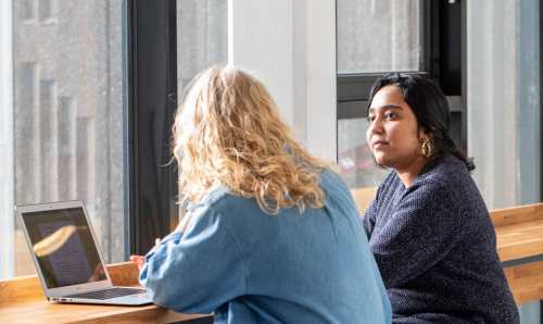 Two students in discussion with a laptop