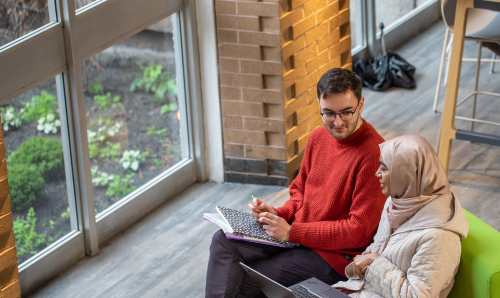 Two students on a sofa in discussion